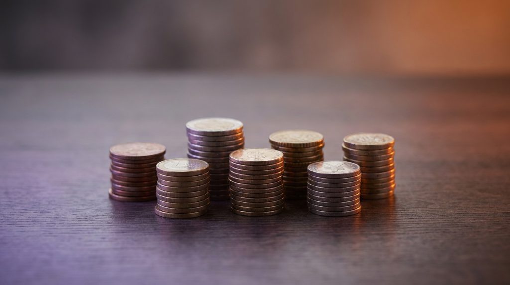 Small stacks of coins from several currencies arranged in a row.
