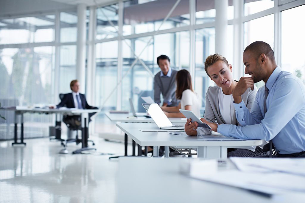 Business colleagues discussing over digital tablet at desk in office