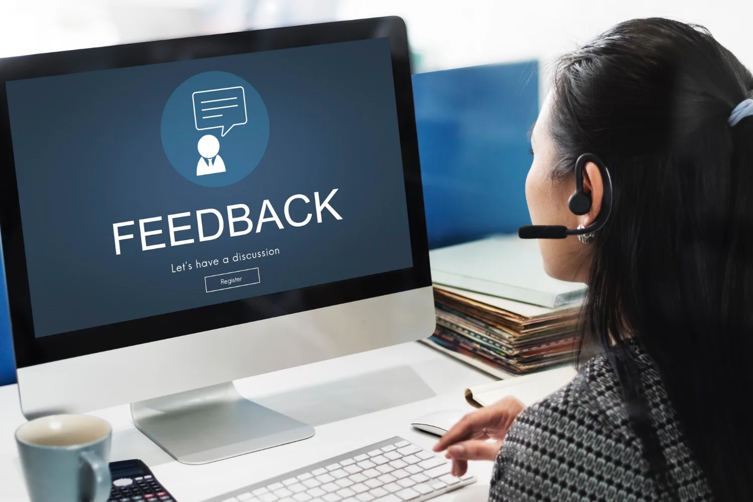 Woman using headset viewing feedback screen on computer for real-time employee communication.