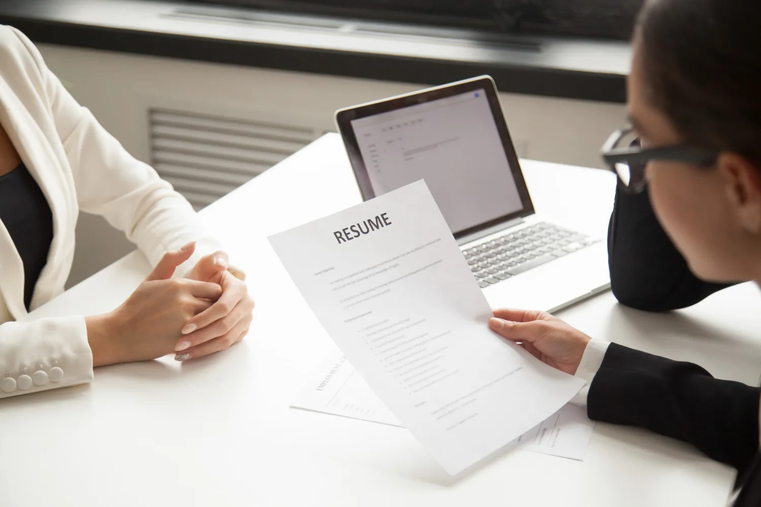 HR professional reviewing a printed resume during a candidate interview - Effortless Resume Management