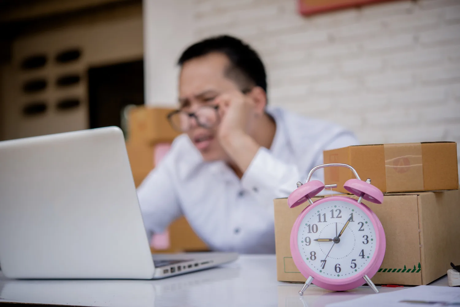 Man viewing work hours on a laptop next to a analog timer clock